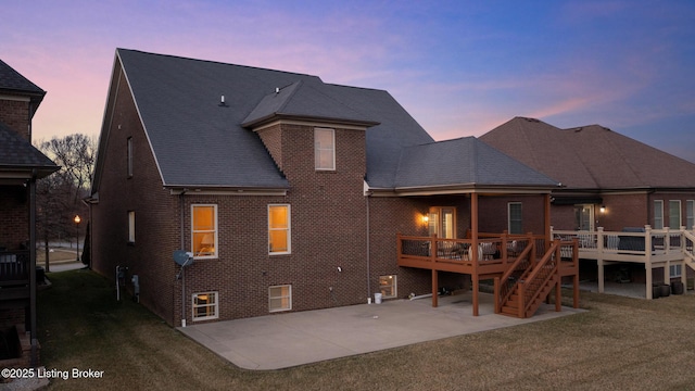 rear view of house with a deck, a patio, brick siding, stairs, and a yard