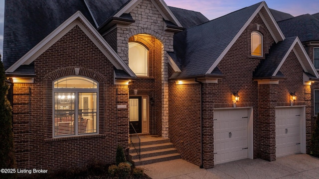 view of front of home with stone siding, brick siding, driveway, and roof with shingles