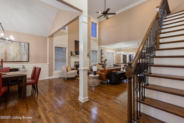 interior space featuring ornamental molding, dark wood-style flooring, a high ceiling, stairs, and a fireplace