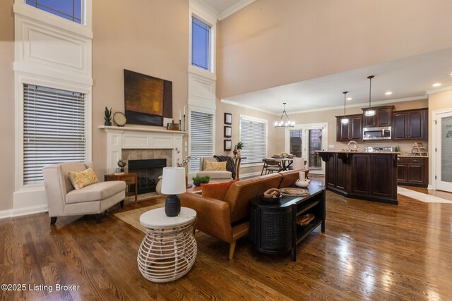 living area featuring dark wood-style floors, a tile fireplace, and crown molding