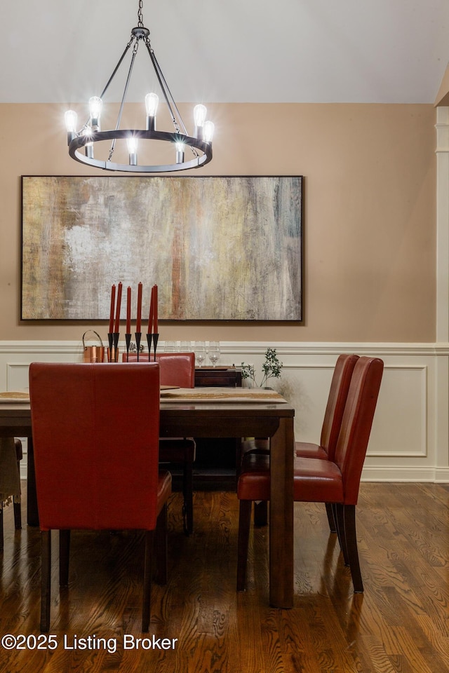 dining room with a wainscoted wall, a decorative wall, wood finished floors, and an inviting chandelier