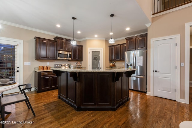 kitchen with appliances with stainless steel finishes, an island with sink, a breakfast bar, and pendant lighting