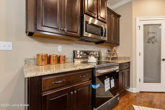 kitchen featuring dark brown cabinetry, light stone counters, dark wood-style flooring, stainless steel appliances, and crown molding