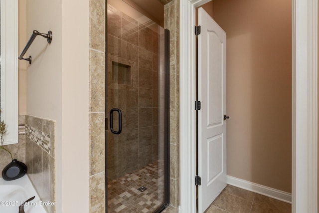 bathroom featuring baseboards, a stall shower, and tile patterned floors