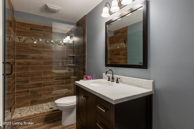 bathroom with toilet, wood finished floors, visible vents, vanity, and a stall shower