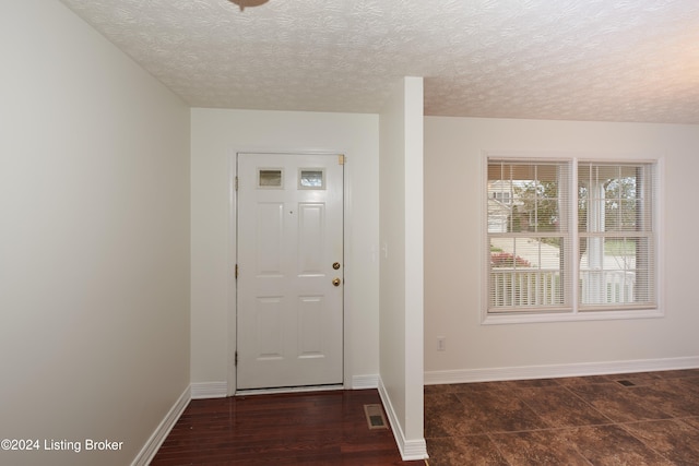 entryway featuring dark wood-type flooring and a textured ceiling