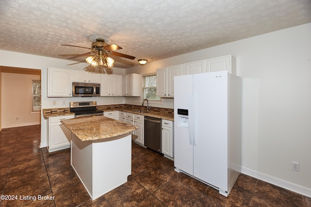 kitchen with a kitchen island, appliances with stainless steel finishes, sink, white cabinets, and a textured ceiling