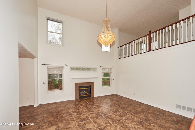 unfurnished living room with a tiled fireplace and a towering ceiling