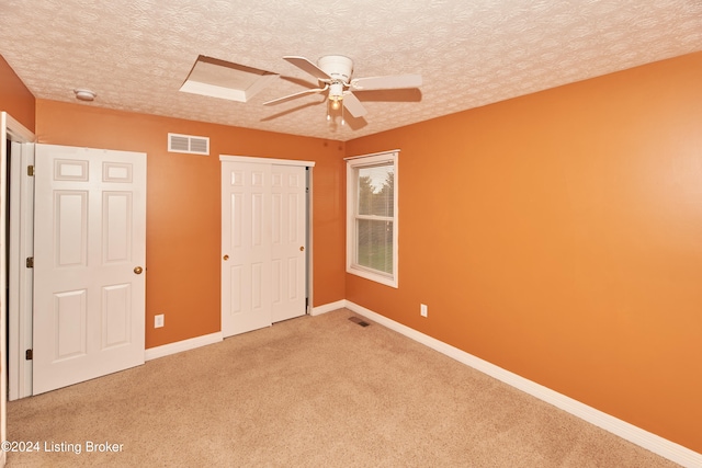 unfurnished bedroom with ceiling fan, carpet floors, a closet, and a textured ceiling