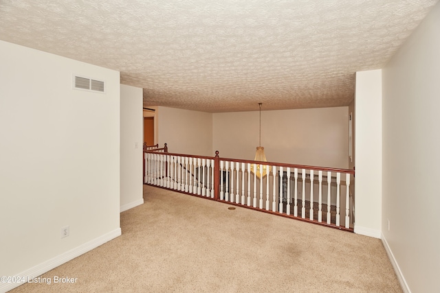 carpeted spare room featuring a textured ceiling