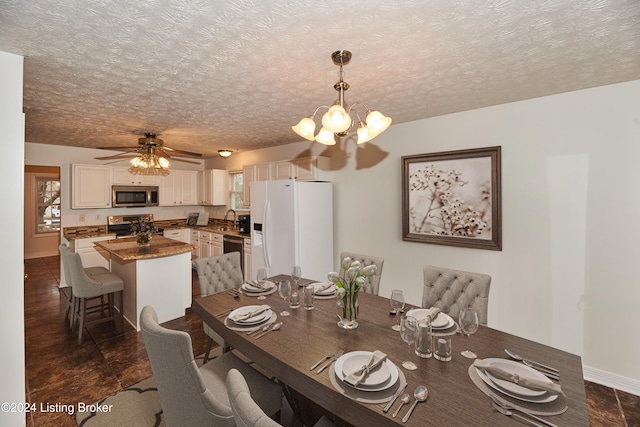 dining space featuring ceiling fan with notable chandelier, sink, and a textured ceiling