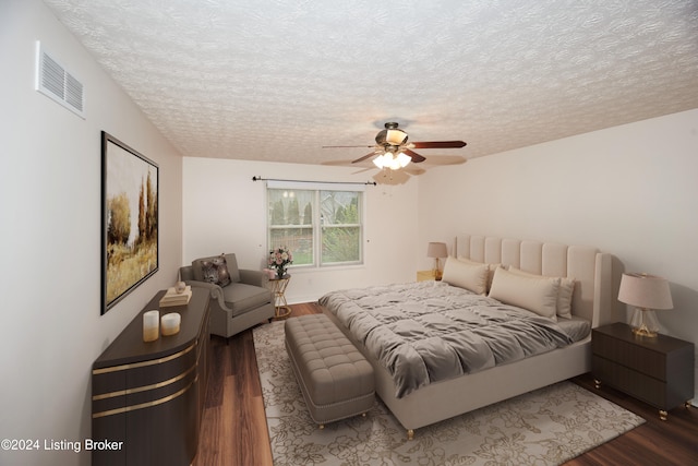 bedroom with dark hardwood / wood-style flooring, ceiling fan, and a textured ceiling