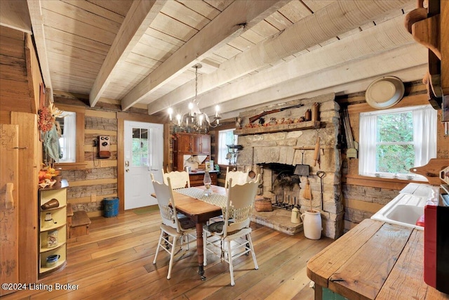 dining space featuring a stone fireplace, beamed ceiling, light hardwood / wood-style floors, wood ceiling, and a chandelier