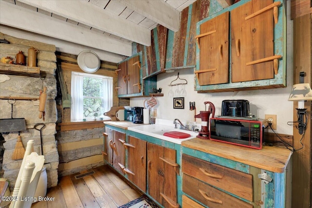 kitchen featuring sink, beamed ceiling, and light wood-type flooring