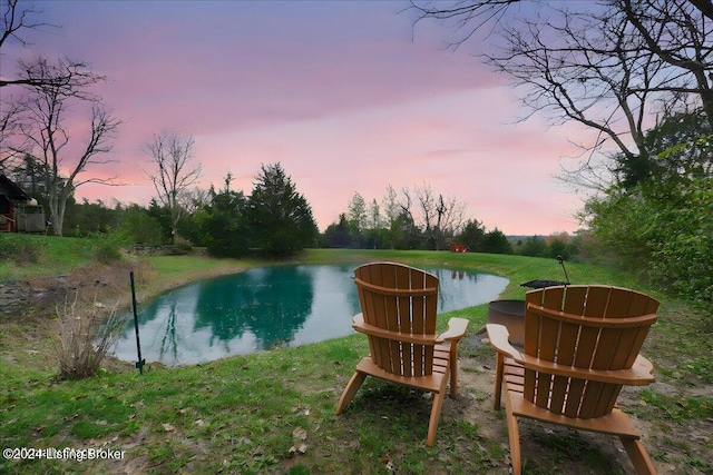 pool at dusk featuring a water view