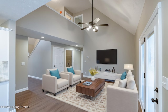 living room featuring ceiling fan, high vaulted ceiling, and light hardwood / wood-style flooring