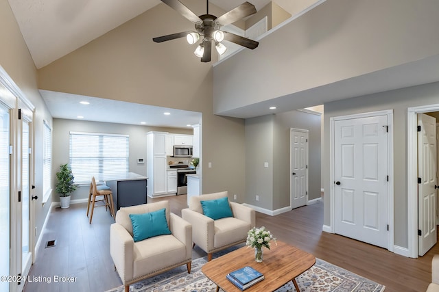 living room with wood-type flooring, high vaulted ceiling, and ceiling fan