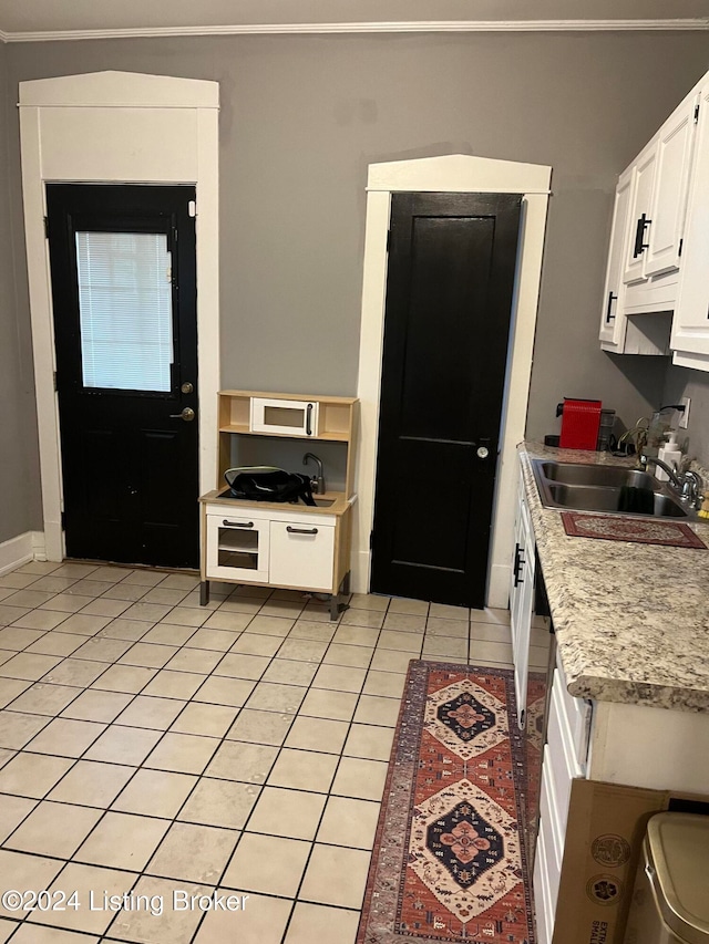 kitchen featuring sink, light tile patterned floors, and white cabinets