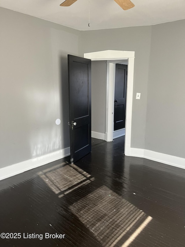 empty room with dark hardwood / wood-style floors and ceiling fan