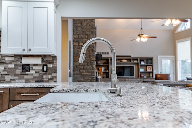 kitchen with white cabinets, sink, vaulted ceiling, ceiling fan, and light stone countertops