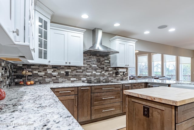 kitchen featuring tasteful backsplash, black electric stovetop, white cabinets, and wall chimney range hood