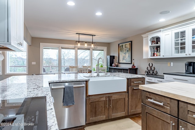 kitchen with light stone counters, stainless steel dishwasher, sink, white cabinetry, and hanging light fixtures