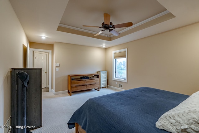 bedroom featuring light colored carpet, a raised ceiling, ceiling fan, and crown molding