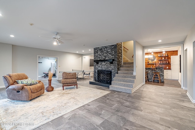 living room featuring ceiling fan, a fireplace, and bar