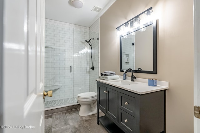 bathroom featuring tile patterned floors, vanity, toilet, and a shower with shower door