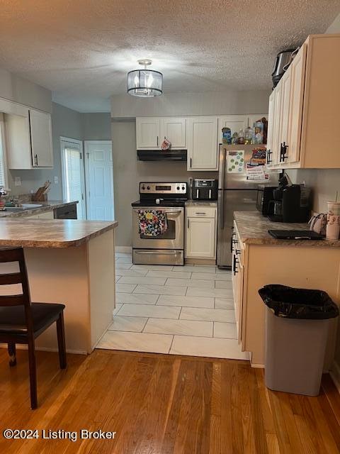 kitchen with white cabinets, appliances with stainless steel finishes, and light wood-type flooring