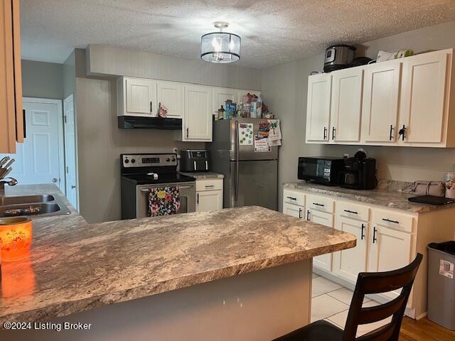 kitchen with white cabinetry, sink, stainless steel appliances, kitchen peninsula, and a textured ceiling