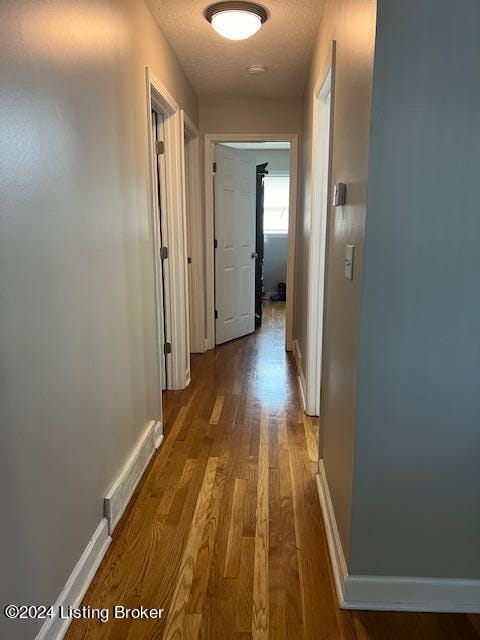 hall with a textured ceiling and dark hardwood / wood-style floors