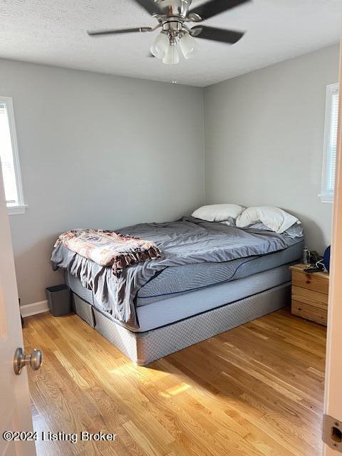 bedroom with a textured ceiling, light wood-type flooring, and ceiling fan