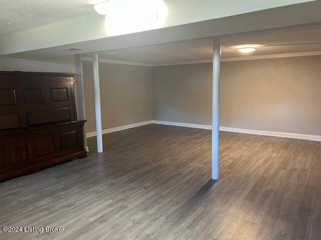 basement featuring a textured ceiling, crown molding, and dark wood-type flooring