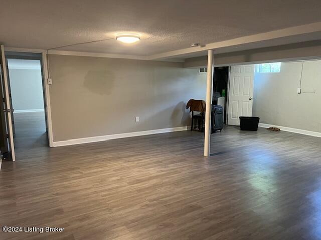 basement with a textured ceiling, crown molding, and dark wood-type flooring