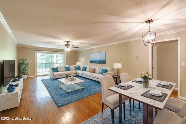 living room with hardwood / wood-style flooring, ceiling fan with notable chandelier, ornamental molding, and a textured ceiling