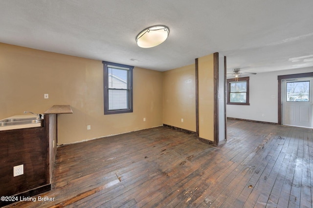 unfurnished living room with dark hardwood / wood-style floors, ceiling fan, and a textured ceiling