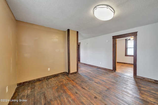 empty room featuring a textured ceiling and dark wood-type flooring