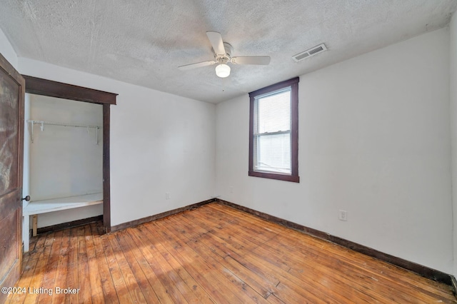 unfurnished bedroom with hardwood / wood-style floors, ceiling fan, a textured ceiling, and a closet