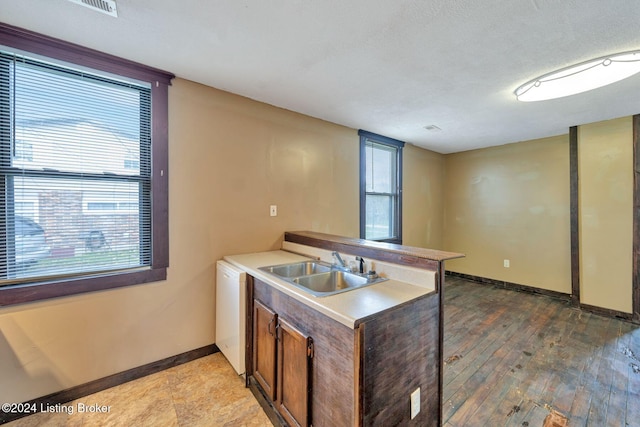 kitchen featuring dishwasher, a textured ceiling, light hardwood / wood-style flooring, and sink