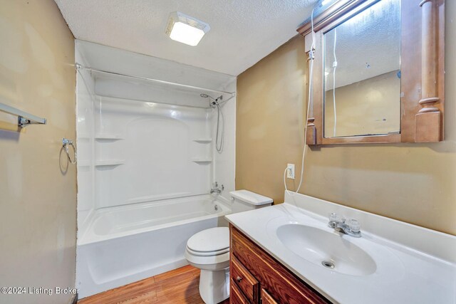 full bathroom featuring vanity, shower / tub combination, toilet, a textured ceiling, and wood-type flooring