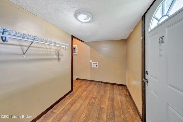 clothes washing area featuring light hardwood / wood-style flooring, washer hookup, and a textured ceiling