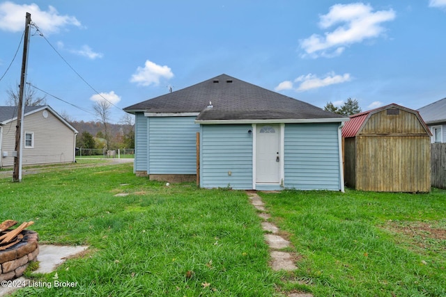 rear view of house with a storage unit and a yard