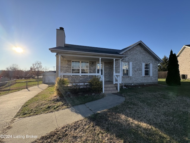 view of front of home featuring central AC, a front lawn, a garage, an outbuilding, and a porch