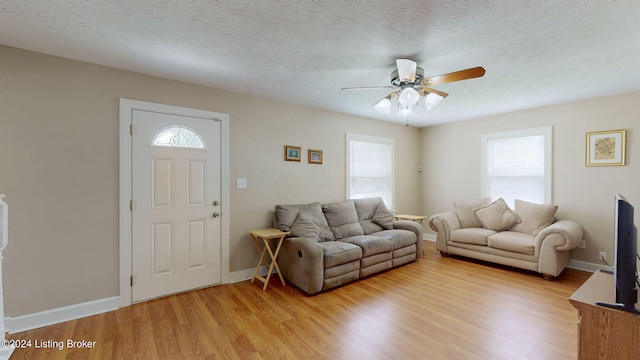 living room featuring hardwood / wood-style floors, ceiling fan, and a textured ceiling