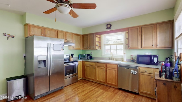 kitchen with appliances with stainless steel finishes, light hardwood / wood-style floors, ceiling fan, and sink