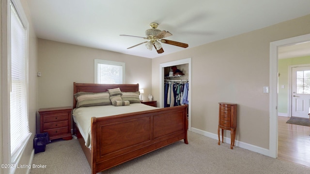 bedroom featuring ceiling fan, a closet, light colored carpet, and multiple windows