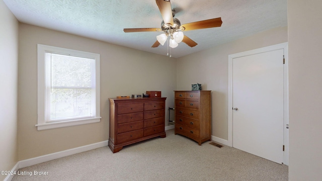 bedroom featuring light carpet, a textured ceiling, and ceiling fan