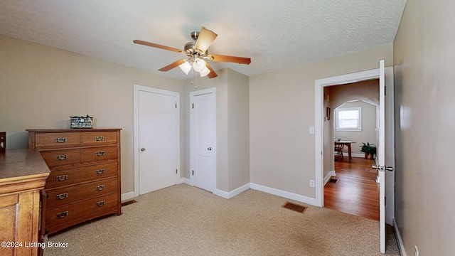 carpeted bedroom featuring ceiling fan and a textured ceiling