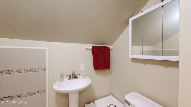 bathroom featuring sink, vaulted ceiling, and toilet